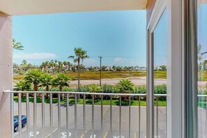 A balcony with a view of a parking lot and palm trees. - Gulfview I #201 - Pool & Hot Tub, Near the Beach (South Padre Island)