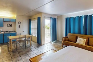 A room with a bed, a sofa, a dining table with chairs, a kitchen area, and a sliding glass door leading to a balcony. - Gulfview I #201 - Pool & Hot Tub, Near the Beach (South Padre Island)