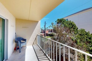 A balcony with a white railing, a blue plastic chair, and a broom leaning against the wall. - Fiesta Sol Condominiums 212 (South Padre Island)