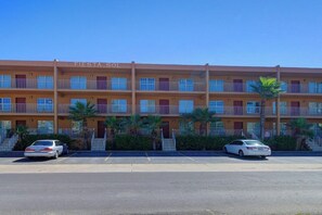 A multi-story motel with a sign reading 'Fiesta Sol' and a parking lot with cars. - Fiesta Sol Condominiums 212 (South Padre Island)