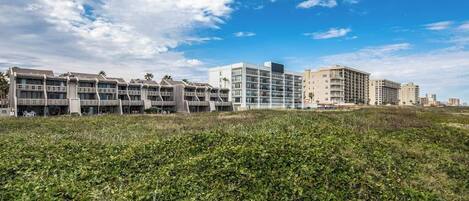 A modern hotel complex with multiple buildings, a grassy foreground, and a clear sky.