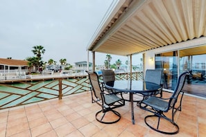 A covered outdoor area with a pool, two chairs, and a table. - Long Island Village 347 Sand Dollar (Port Isabel)