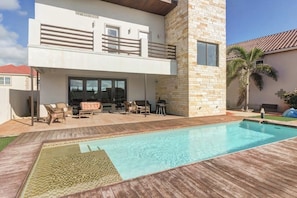 A modern two-story house with a swimming pool, outdoor furniture, and a stone facade. - Harbor Island Beach House #1533 (Port Isabel)