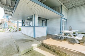 A covered outdoor area with a concrete floor, a wooden picnic table, and a railing. - Tiki Hideaway - Canal-Front, Big Deck & Dogs OK (Tiki Island)