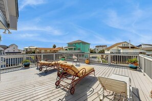 Um deck de madeira com móveis de exterior, incluindo uma espreguiçadeira e uma mesa pequena.