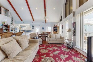 Uma sala de estar ampla com um tapete vermelho estampado, um sofá bege e uma área de jantar com mesa e cadeiras.