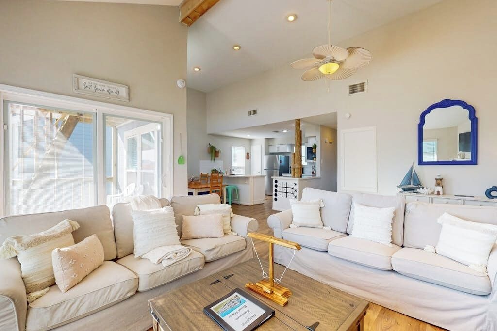 A spacious living area with a large sofa set, a coffee table, and a ceiling fan.
