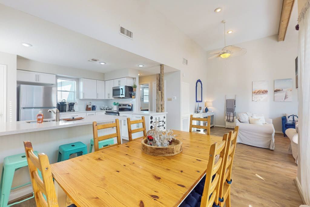 Una cocina moderna con armarios blancos, una mesa de comedor de madera y una isla central con microondas.