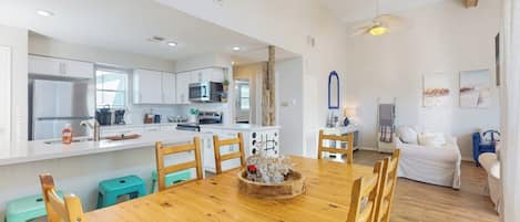 Una cocina moderna con armarios blancos, una mesa de comedor de madera y una isla central con microondas.
