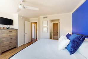 A bedroom with a bed, a dresser, a ceiling fan, and a television. - Ocean Breeze Getaway (Galveston)