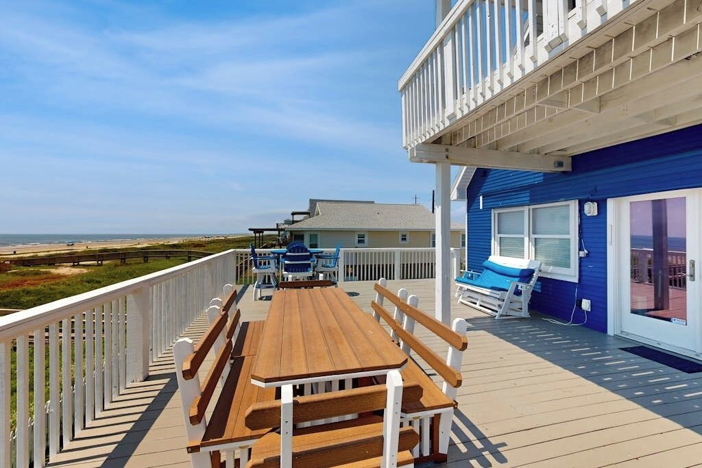 Une terrasse avec une table et des bancs en bois, donnant sur une plage.
