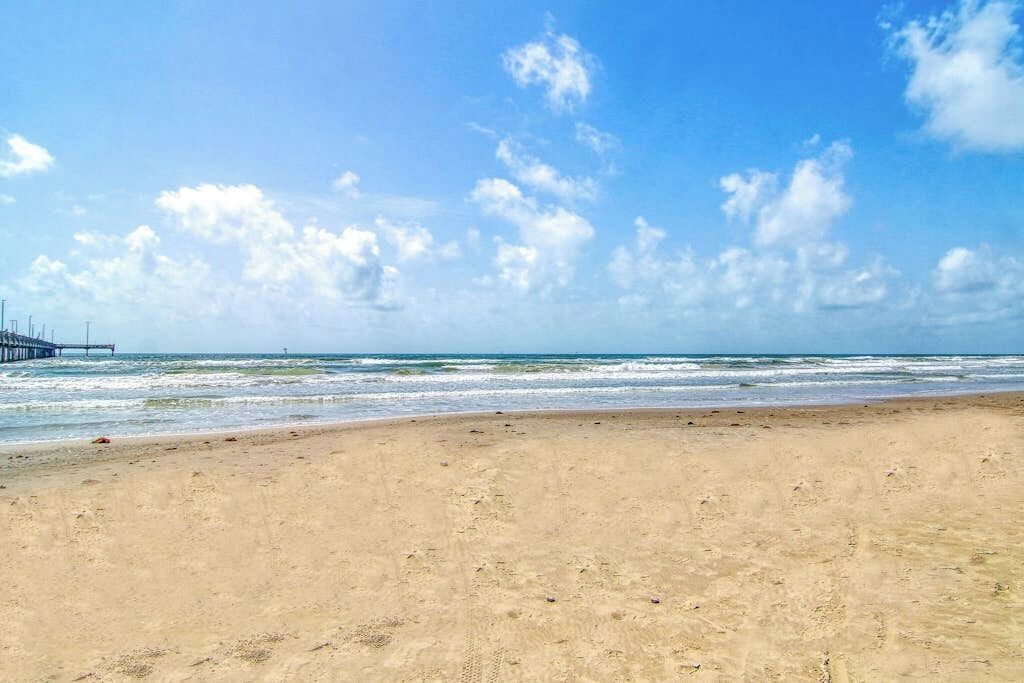 Ein Strand mit einem Steg, der ins Wasser ragt.