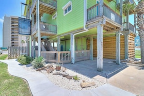 A multi-story building with balconies, a covered porch, and a staircase leading to the upper floors. - Gulf Breezes Entire Home (Port Aransas)