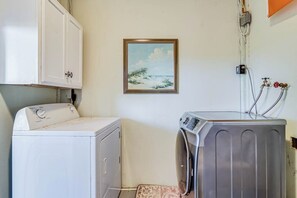 A laundry room with a washing machine, dryer, and a wall-mounted water heater. - Gulf Breezes Entire Home (Port Aransas)