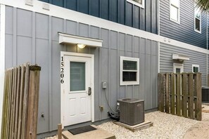 En boligbygning med en hvid dør, et lille vindue og en udendørs aircondition.