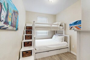 A bunk bed with storage drawers, a window with blinds, and artwork on the walls. - Tiki House - Ocean Views, Pool, Steps to Beach (Corpus Christi)