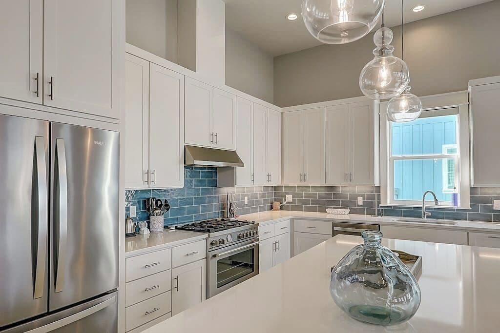 Una cocina moderna con gabinetes blancos, electrodomésticos de acero inoxidable y una isla grande.