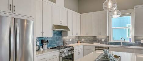 A modern kitchen with white cabinets, stainless steel appliances, and a large island.