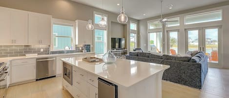 A modern kitchen with white cabinetry, a central island, and pendant lighting.