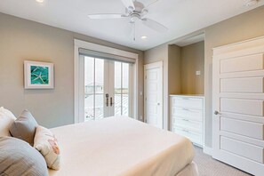 A bedroom with a bed, a ceiling fan, a door, and a window. - My Happy Place - Waterfront, Pool & Kayaks (Rockport)