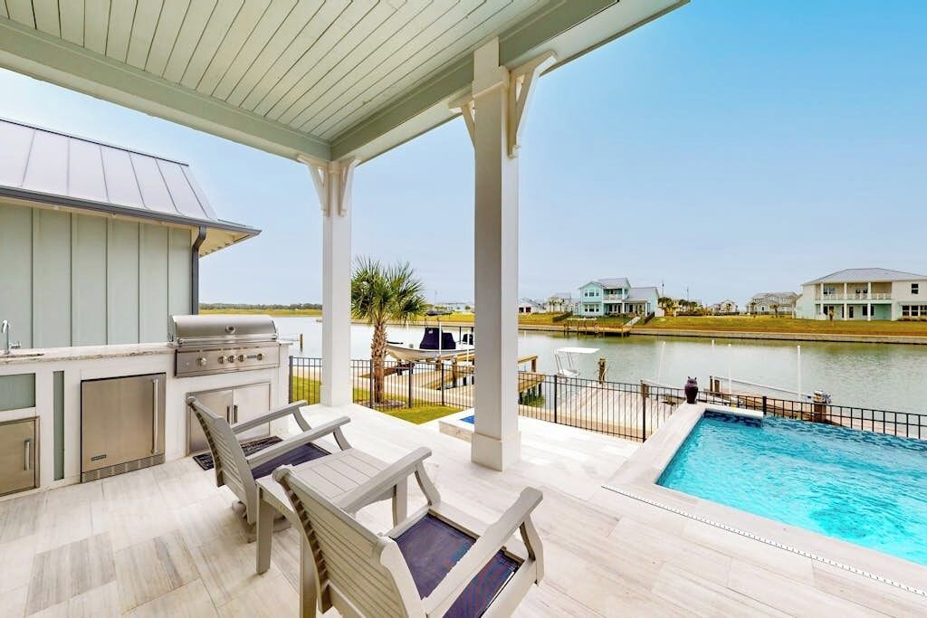 An outdoor patio with a pool, a grill, and seating.