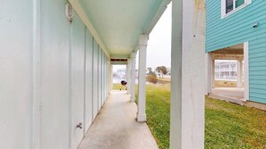 A covered walkway leading to a building with a light blue exterior. - Bella Vista #25 - Water Views, Pool & Hot Tub (Port Aransas)
