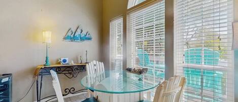 A dining area with a glass table and chairs, a lamp, and a wall with decorative items.