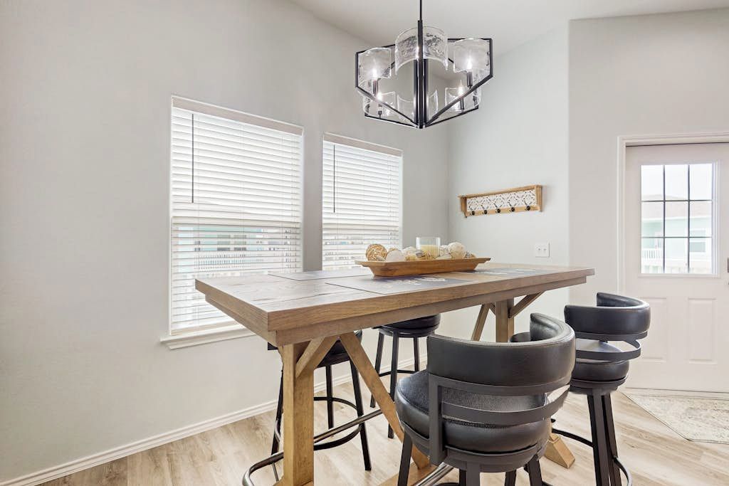 A dining area with a wooden table, black chairs, and a chandelier.