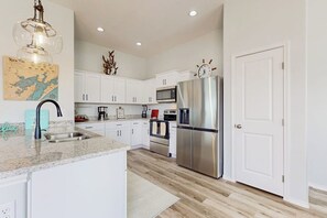 A modern kitchen with white cabinets, stainless steel appliances, and a granite countertop. - Blue Diamond Cottage (Rockport)