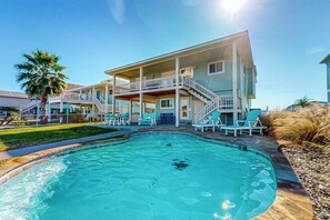 A two-story building with a swimming pool, outdoor seating, and a palm tree. - The Seashell Getaway (Rockport)