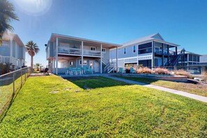A two-story building with a balcony, a covered patio area, and a well-maintained lawn. - The Seashell Getaway (Rockport)