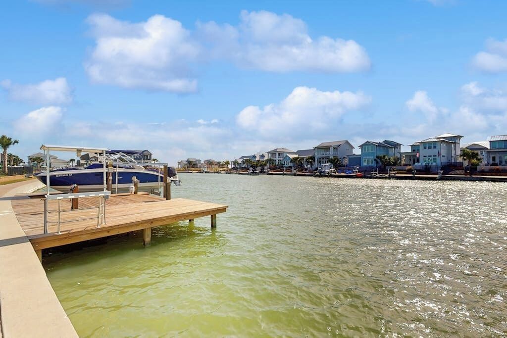 Un port de plaisance avec un quai en bois, des bateaux et des maisons situées au bord de l’eau.