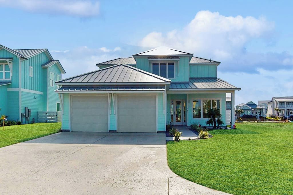 Une maison à deux étages avec un garage, une véranda et une pelouse bien entretenue.