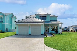 A two-story house with a garage, a covered porch, and a well-maintained lawn. - Tortuga Palms - Bayfront, Heated Pool & Hot Tub (Rockport)