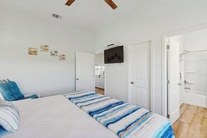 A bedroom with a bed, a television, and a door leading to another room. - Paradise on the Coast (Rockport)