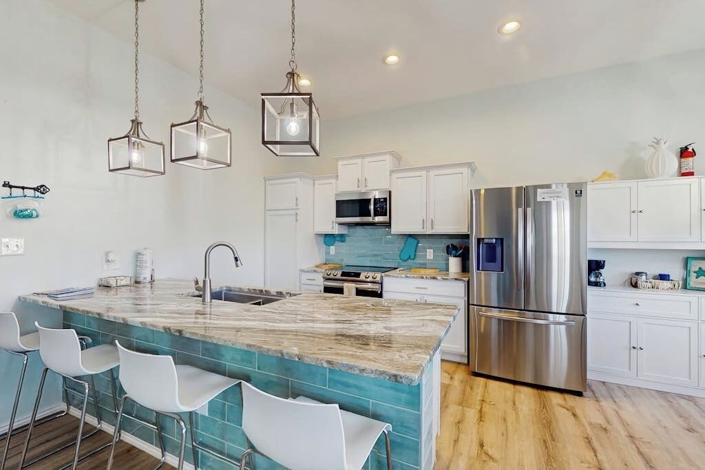 A modern kitchen with white cabinets, stainless steel appliances, and a central island with bar stools.