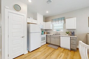 Eine Küche mit weißen Schränken, einem Kühlschrank, einem Backofen und einem Geschirrspüler.