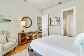 Ein Schlafzimmer mit einem großen Bett, einem Nachttisch, einer Lampe und einem Bücherregal.