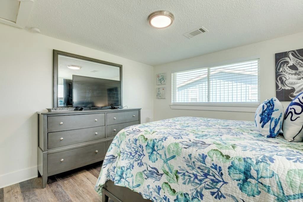 A bedroom with a bed, dresser, and window with blinds.