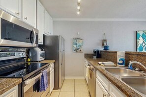 Une cuisine de taille réduite équipée d’un four à micro-ondes, d’une cuisinière, d’un réfrigérateur et d’un évier.