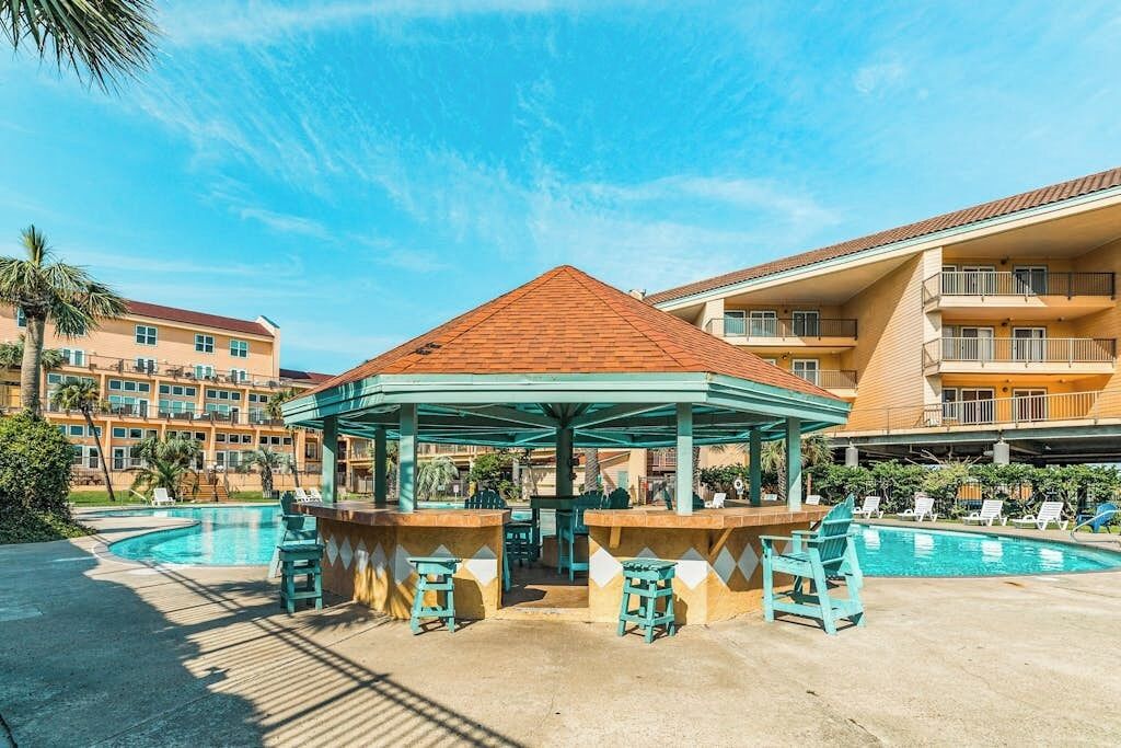 Un espace aménagé au bord de la piscine, comprenant un kiosque, des chaises longues et une piscine.
