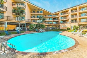 A multi-story hotel with a swimming pool, outdoor seating, and balconies. - Maravilla Condos - Anchors Away (Galveston)