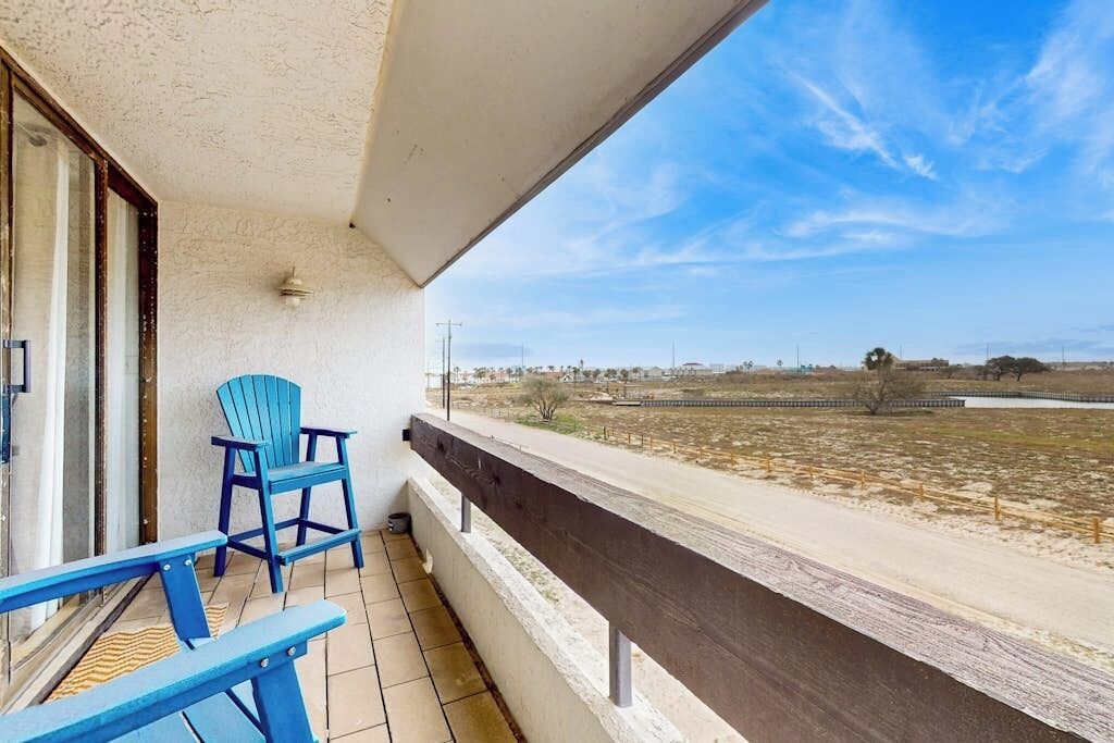 A balcony with a view of a flat landscape, a chair, and a table.
