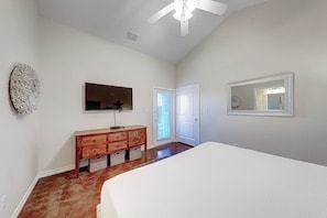 A bedroom with a bed, a dresser, a television, and a ceiling fan. - Anegada Village - Love & Luck (Corpus Christi)