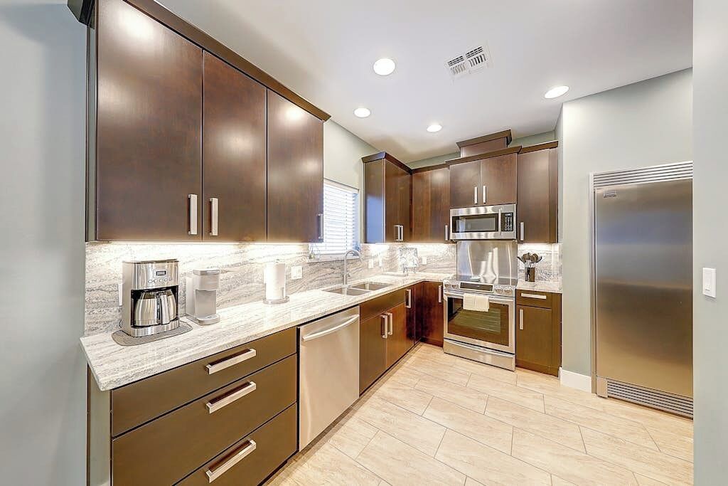 A modern kitchen with stainless steel appliances, a marble countertop, and wooden cabinets.