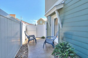 A patio area with two chairs, a small plant, and a white fence. - Serenity Island - Two-Story, Pool, Near the Beach (Corpus Christi)