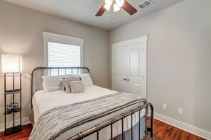 Ein Schlafzimmer mit Bett, Nachttisch, Lampe, Fenster und Kleiderschrank.