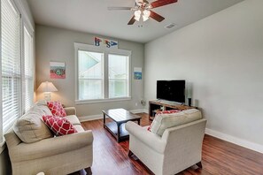 Ein Wohnzimmer mit zwei Sofas, einem Couchtisch, einem Fernseher und einem Deckenventilator.