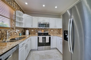 A modern kitchen with white cabinets, a stainless steel refrigerator, a microwave, and a double oven. - Stunning Sunsets & Snorkelling on 7 Mile (George Town)