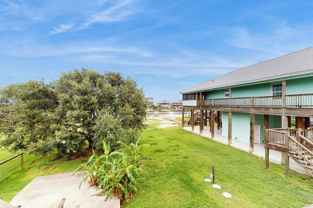 A hotel with a covered outdoor area, a grassy lawn, and a large tree.